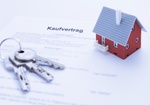 Hausmodell und Schluessel auf Kaufvertrag