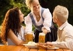 Kellnerin und zwei Gäste im Biergarten